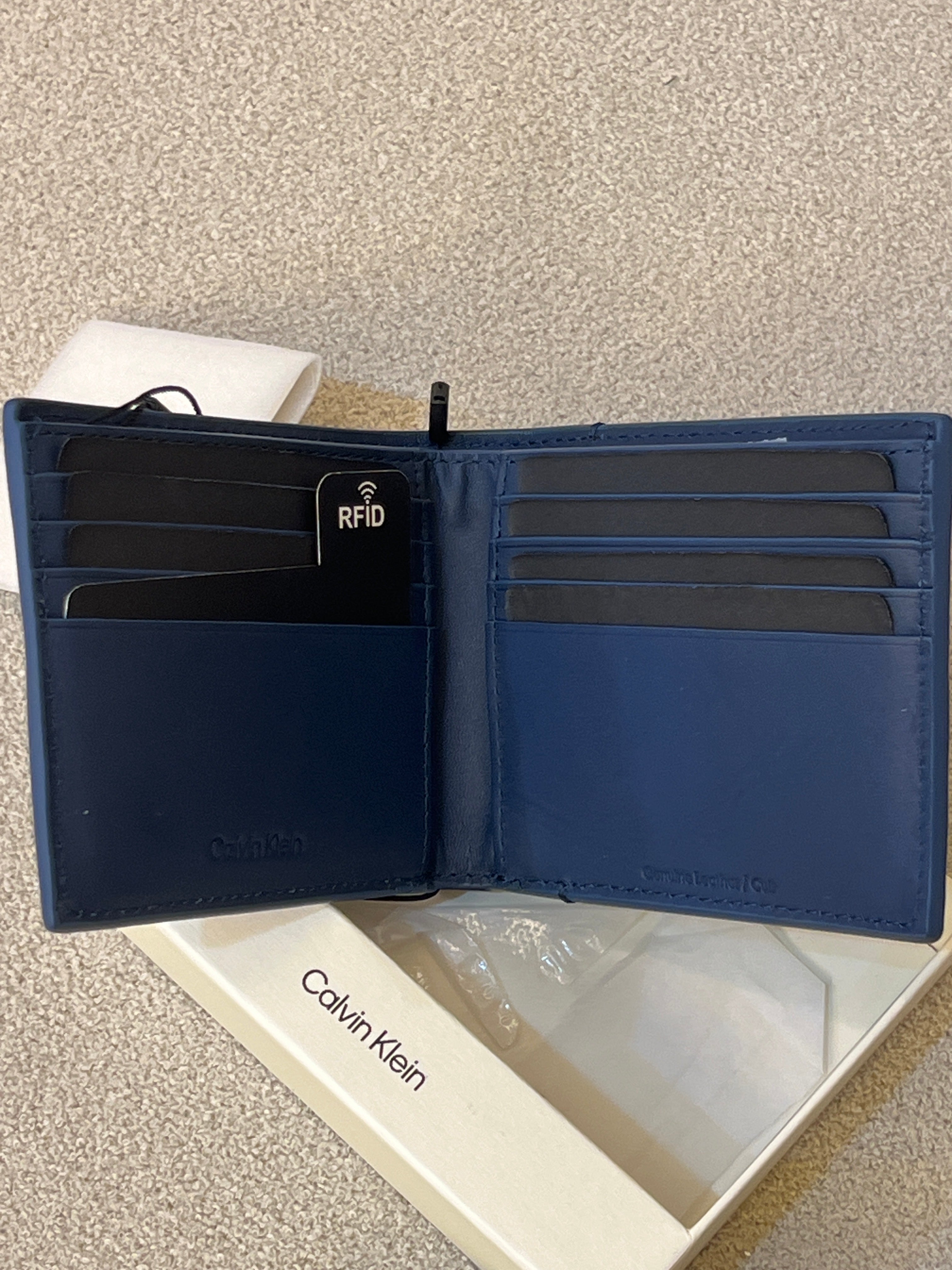 Calvin Klein wallet features a minimalist design with a small silver logo stud on the corner