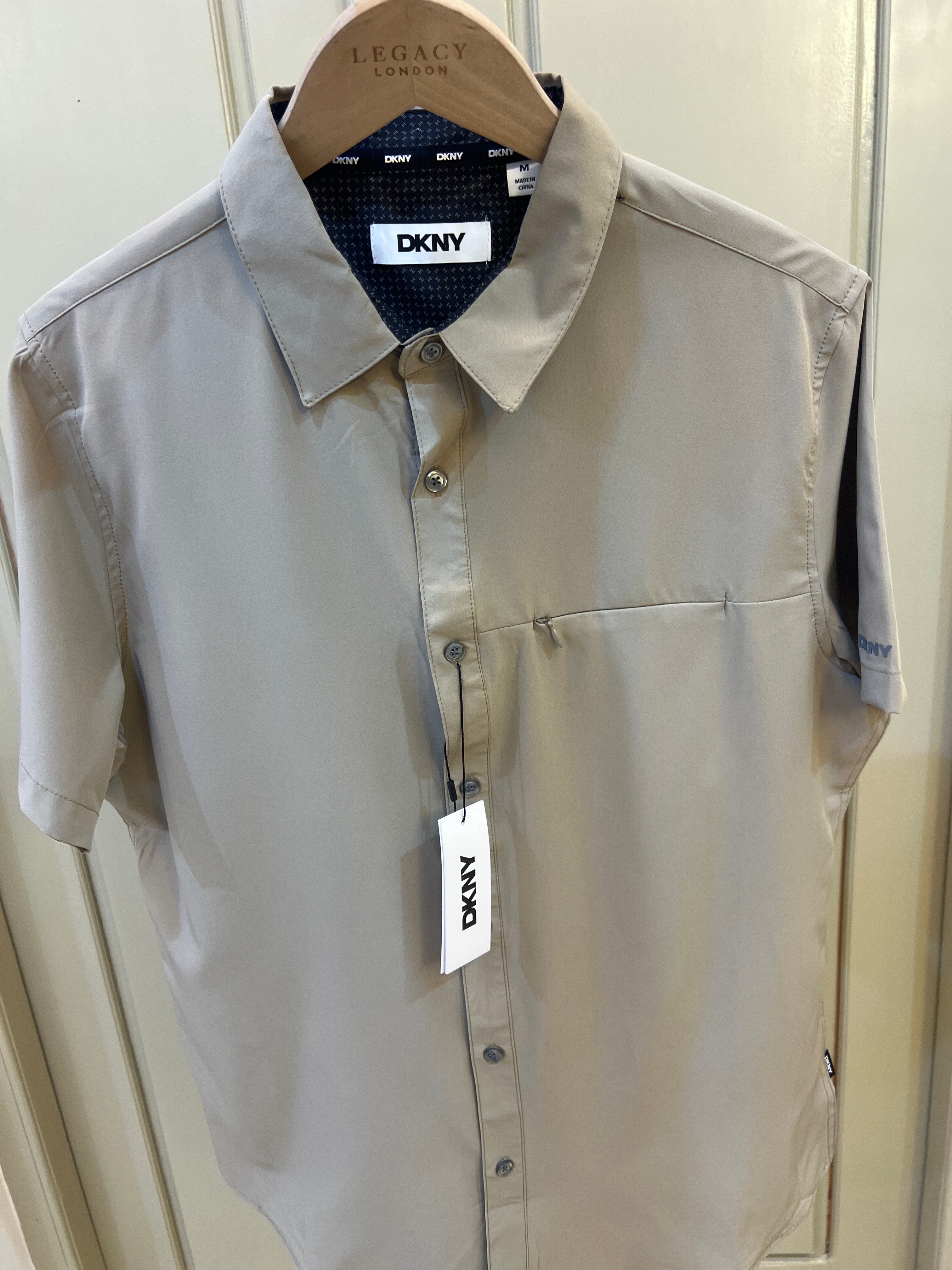 DKNY short-sleeve button-up shirt features a dark inner collar lining and a chest pocket