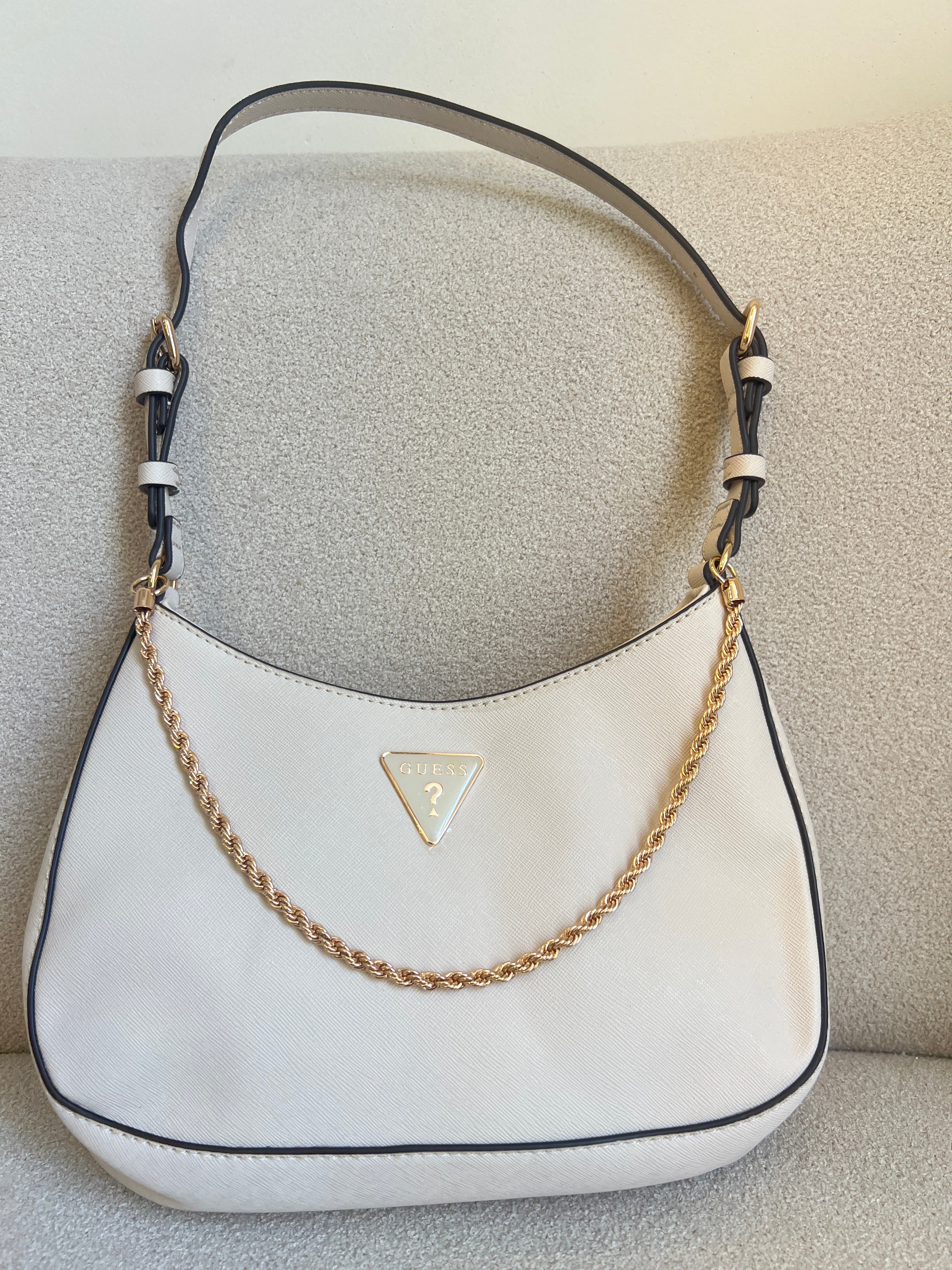 GUESS Noelle Saffiano Shoulder Bag in bone white features a gold-tone chain strap and a signature triangular logo plaque