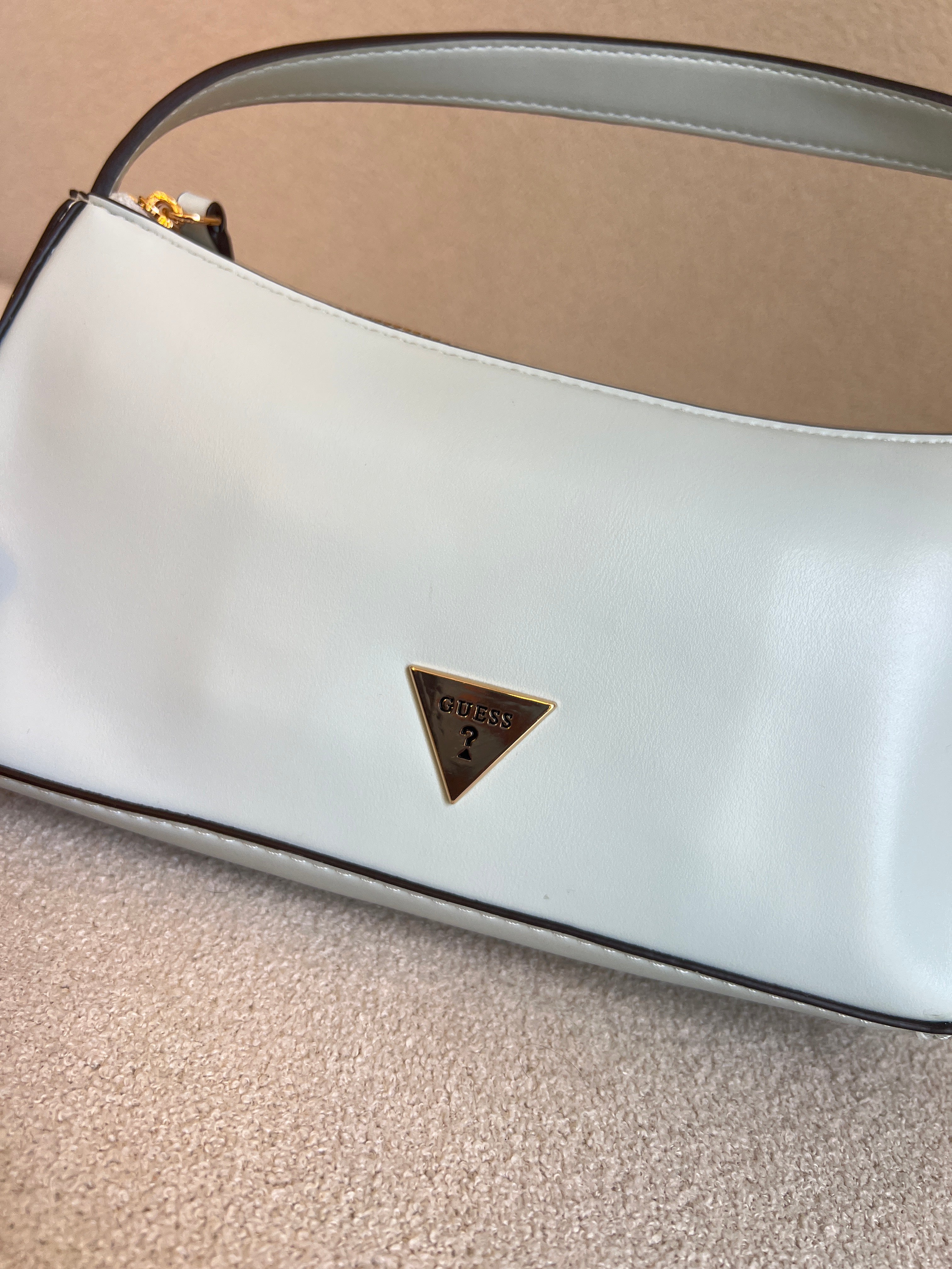 GUESS Tasha Mini Shoulder bag features a light blue synthetic exterior and a polished gold-tone triangular logo plaque