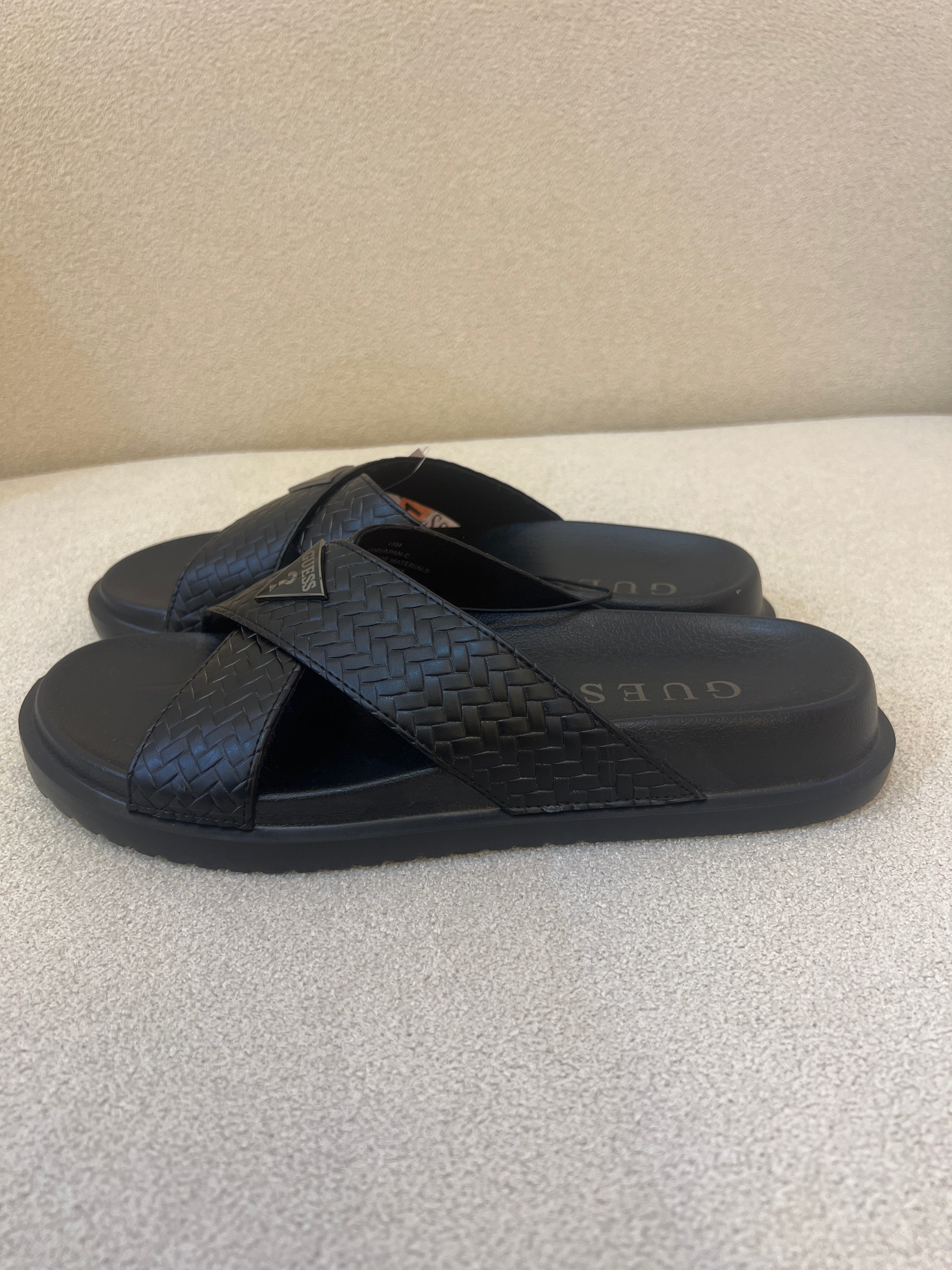 GUESS black Banlin slide sandals featuring a woven design and a silver triangular logo