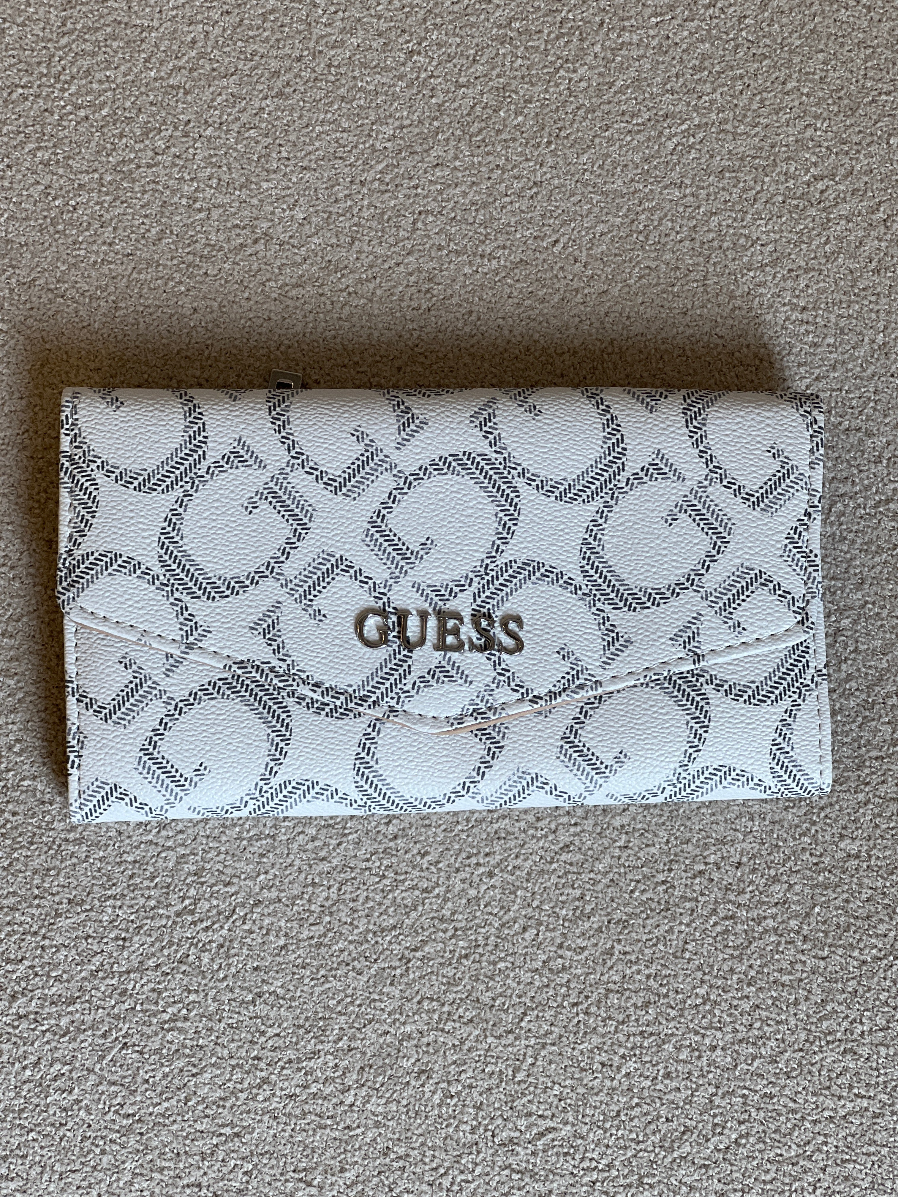 Guess Granby SLG Slim Clutch features an all-over logo print and a snap button closure