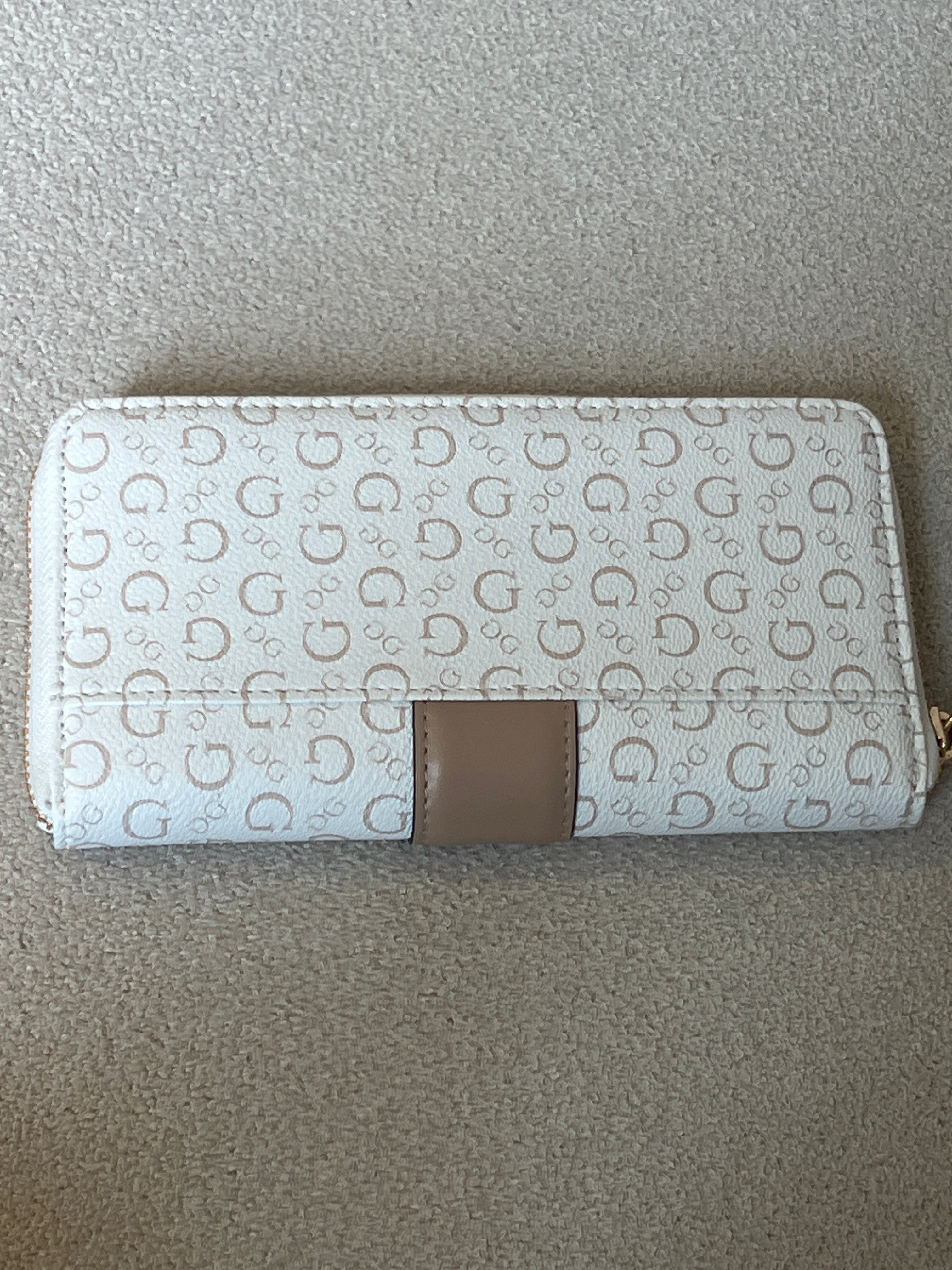 Guess Isabella zip-around wallet features a white printed design with a tan center strap and a prominent gold logo plaque