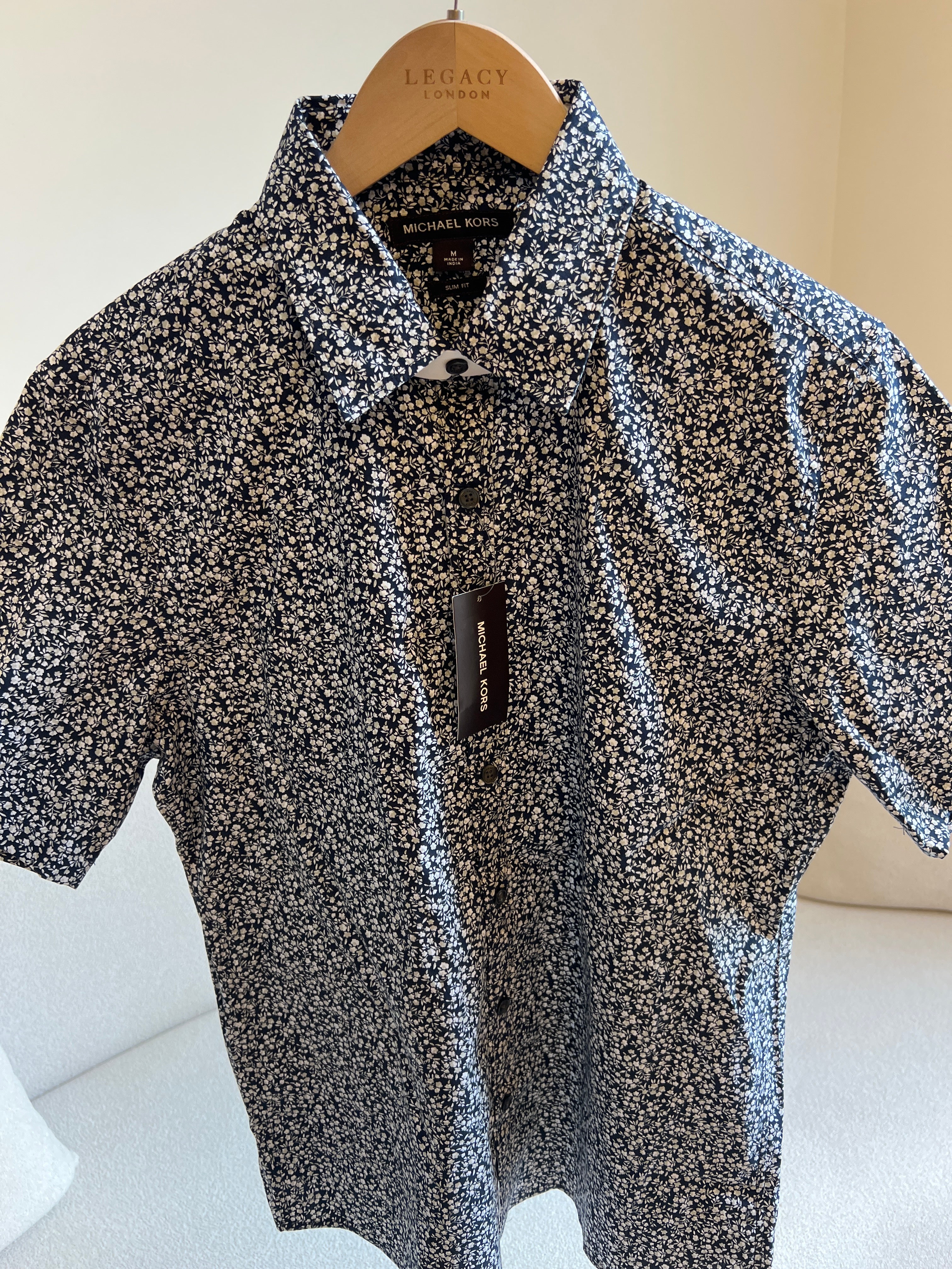 Michael Kors men's black and white floral print short-sleeve shirt features a slim fit and stretch fabric for comfort