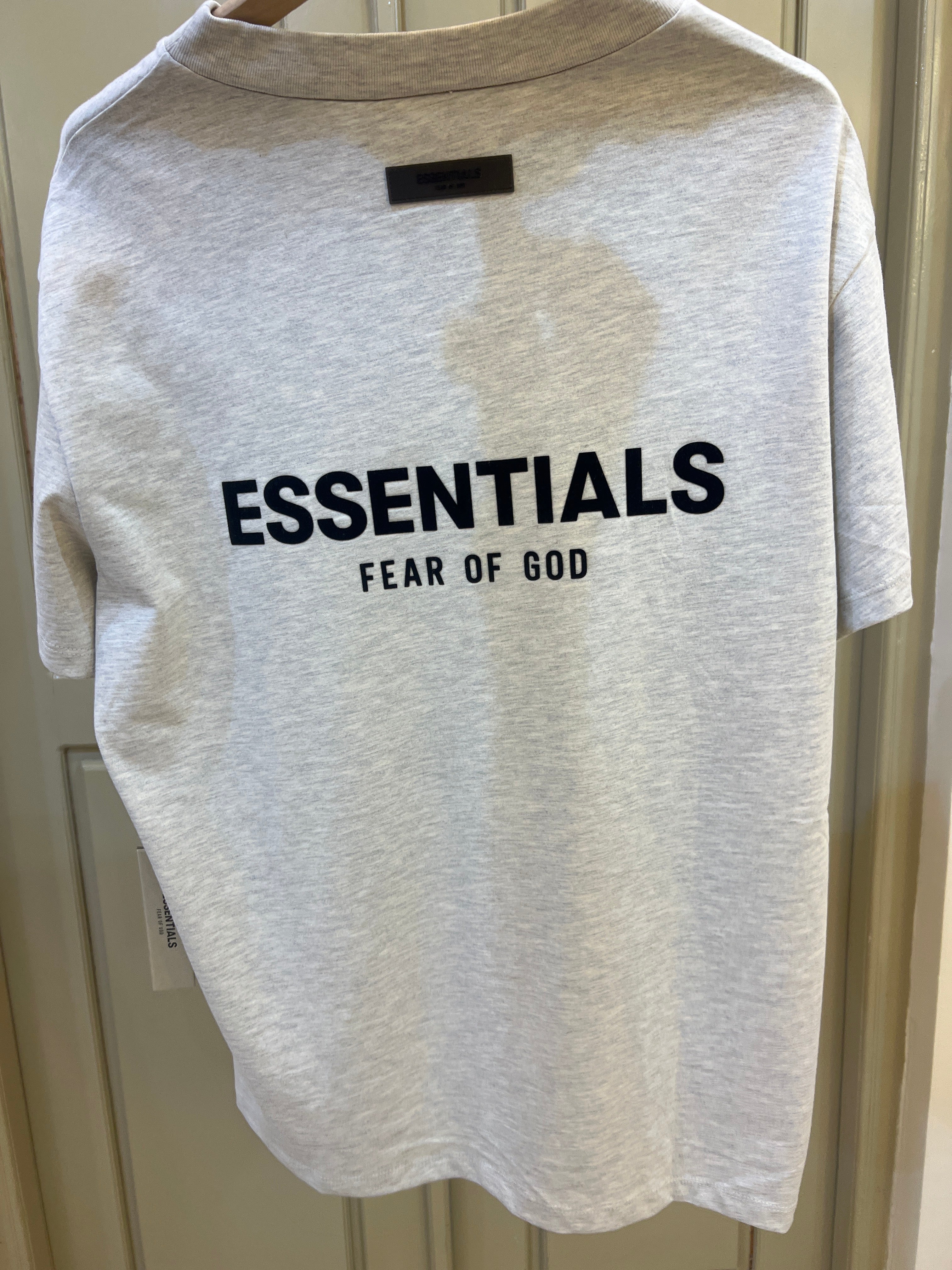 Fear of God Essentials T-shirt in light oatmeal features a distinct black logo graphic on the chest
