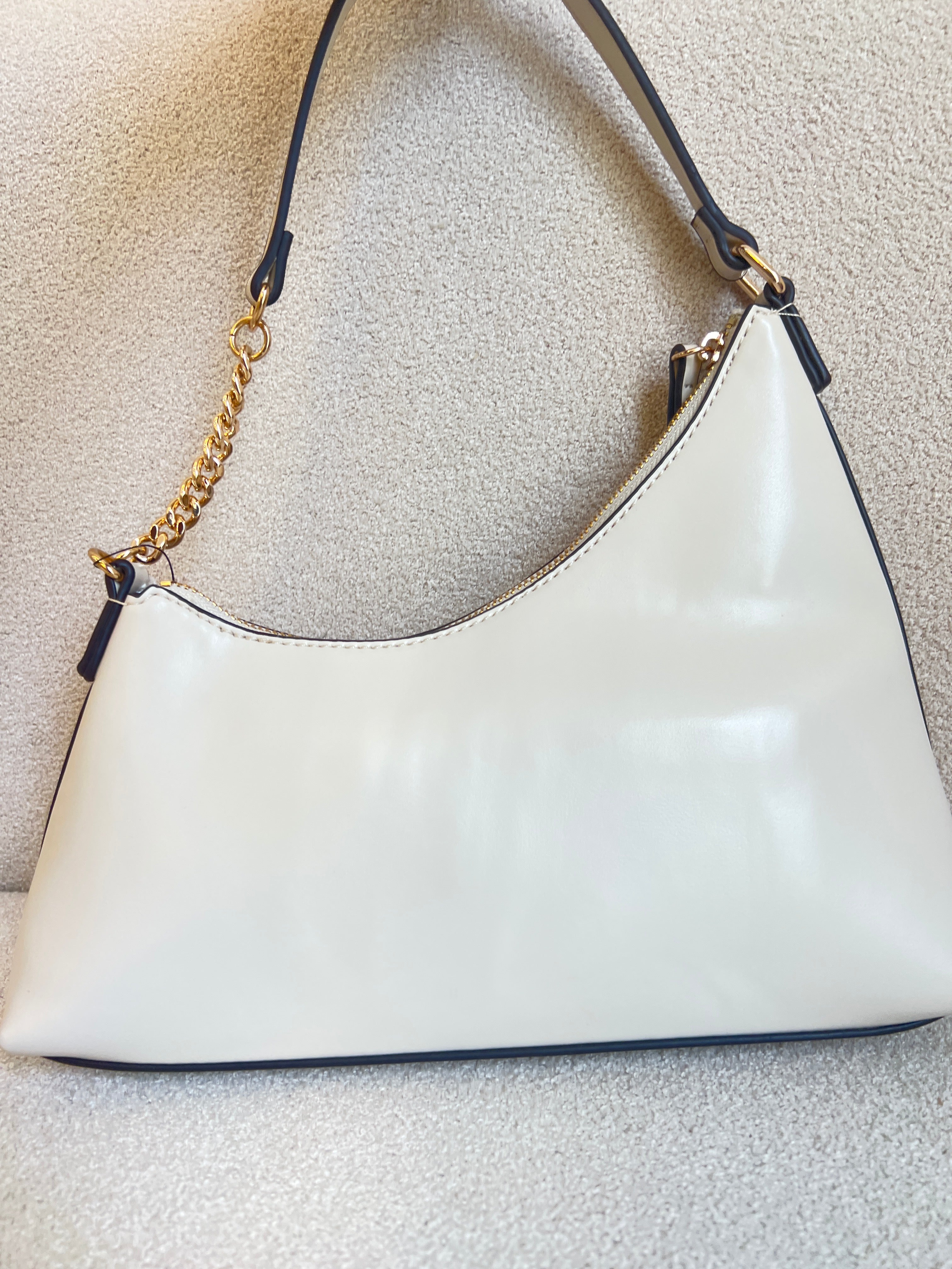 Guess Noelle top zip shoulder bag features a sleek white faux leather exterior with a distinctive triangular logo plaque