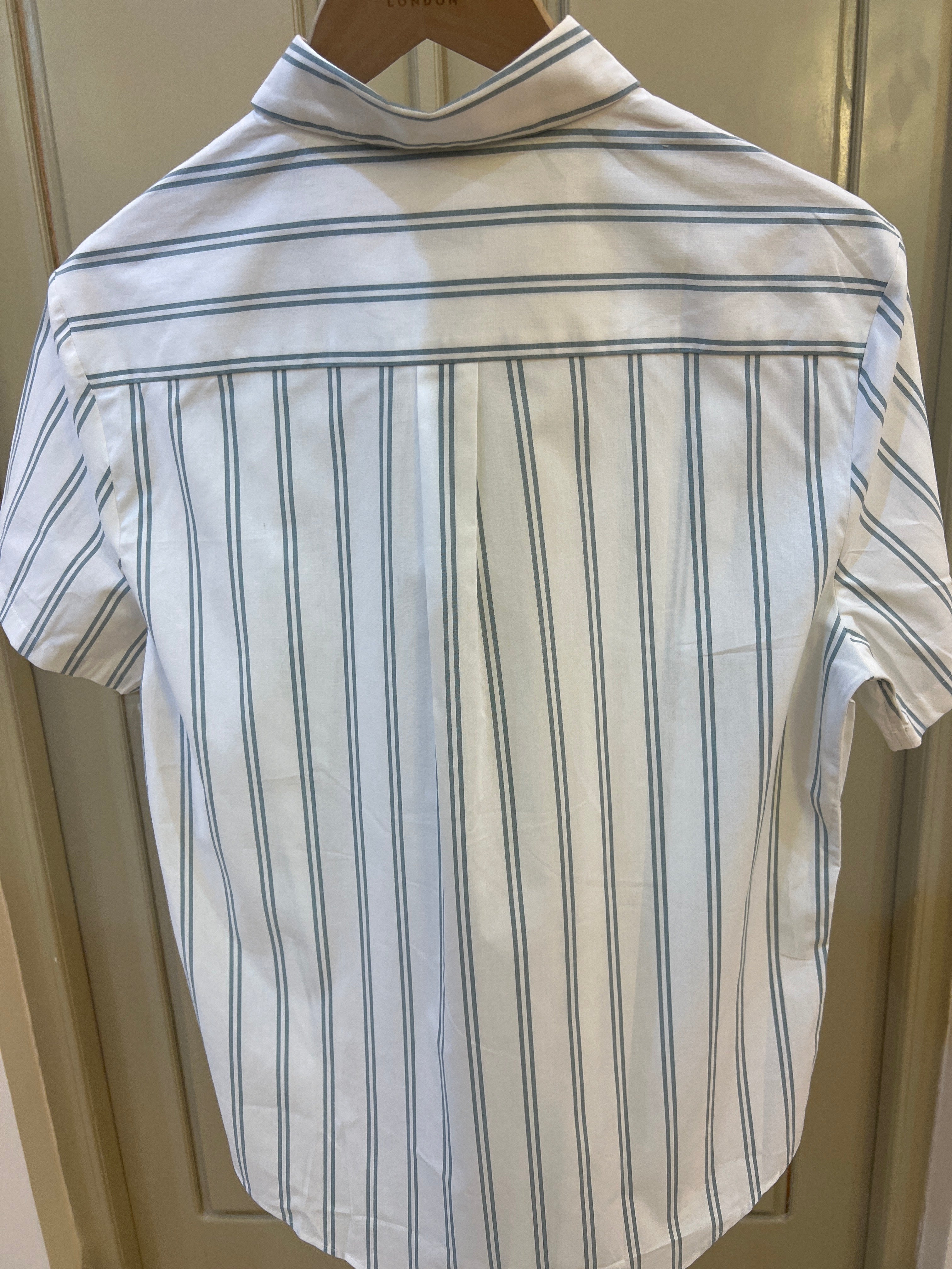 Calvin Klein short-sleeve button-down shirt features a crisp white fabric adorned with thin grey vertical stripes and a small embroidered logo on the chest