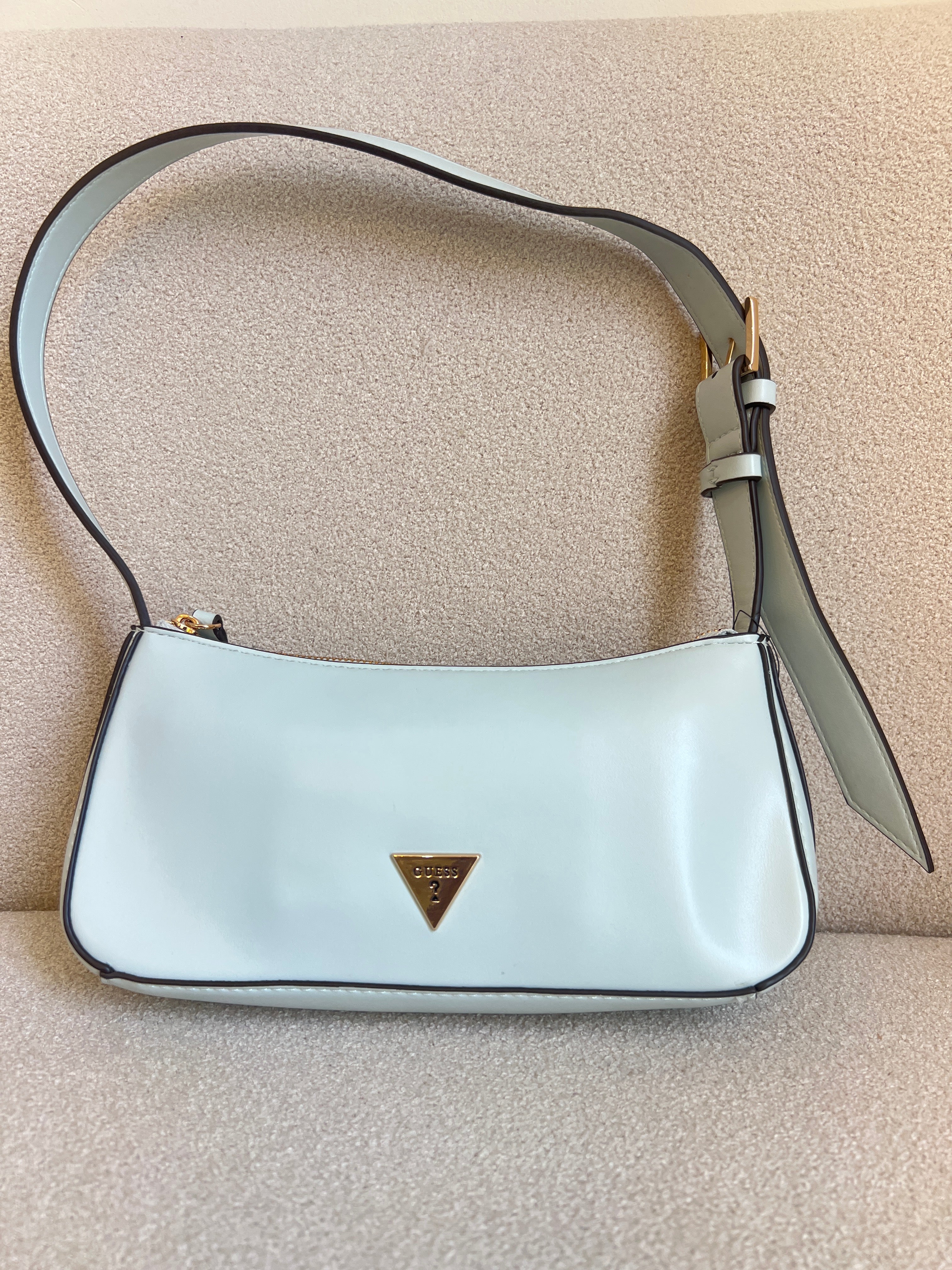 GUESS Tasha Mini Shoulder bag features a light blue synthetic exterior and a polished gold-tone triangular logo plaque