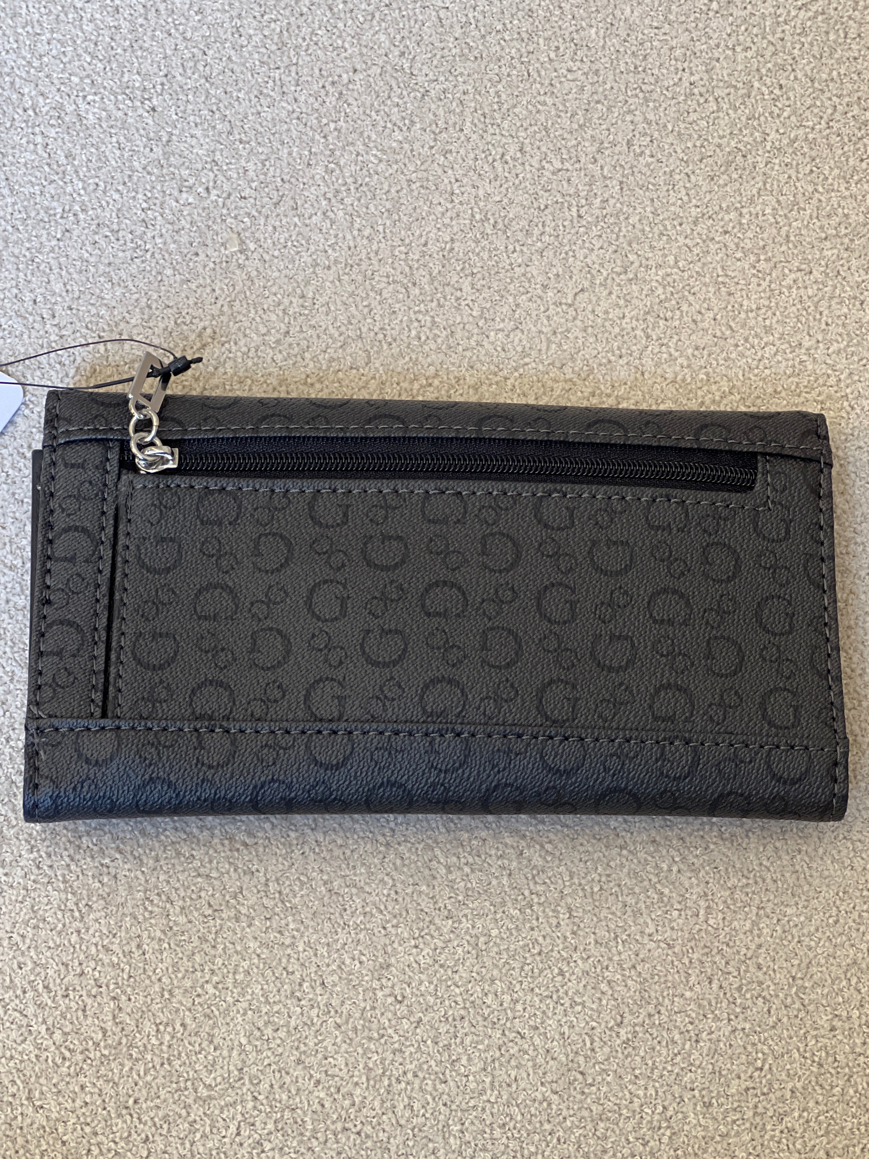 Guess clutch wallet featuring an all-over monogram logo print and a snap-flap closure
