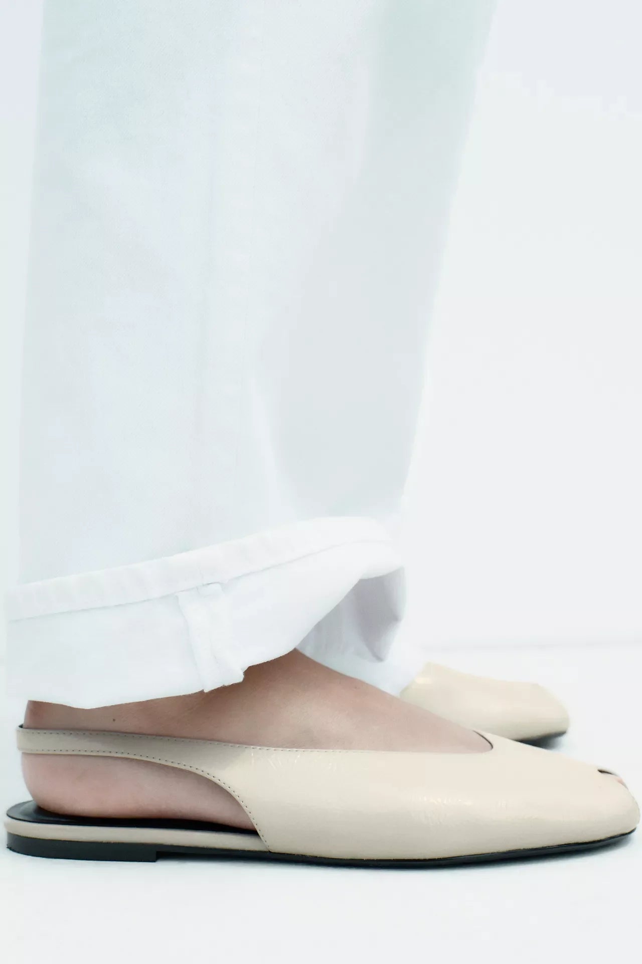 cream-colored Zara pointed-toe slingback flats feature a patent leather finish and an elasticated heel strap