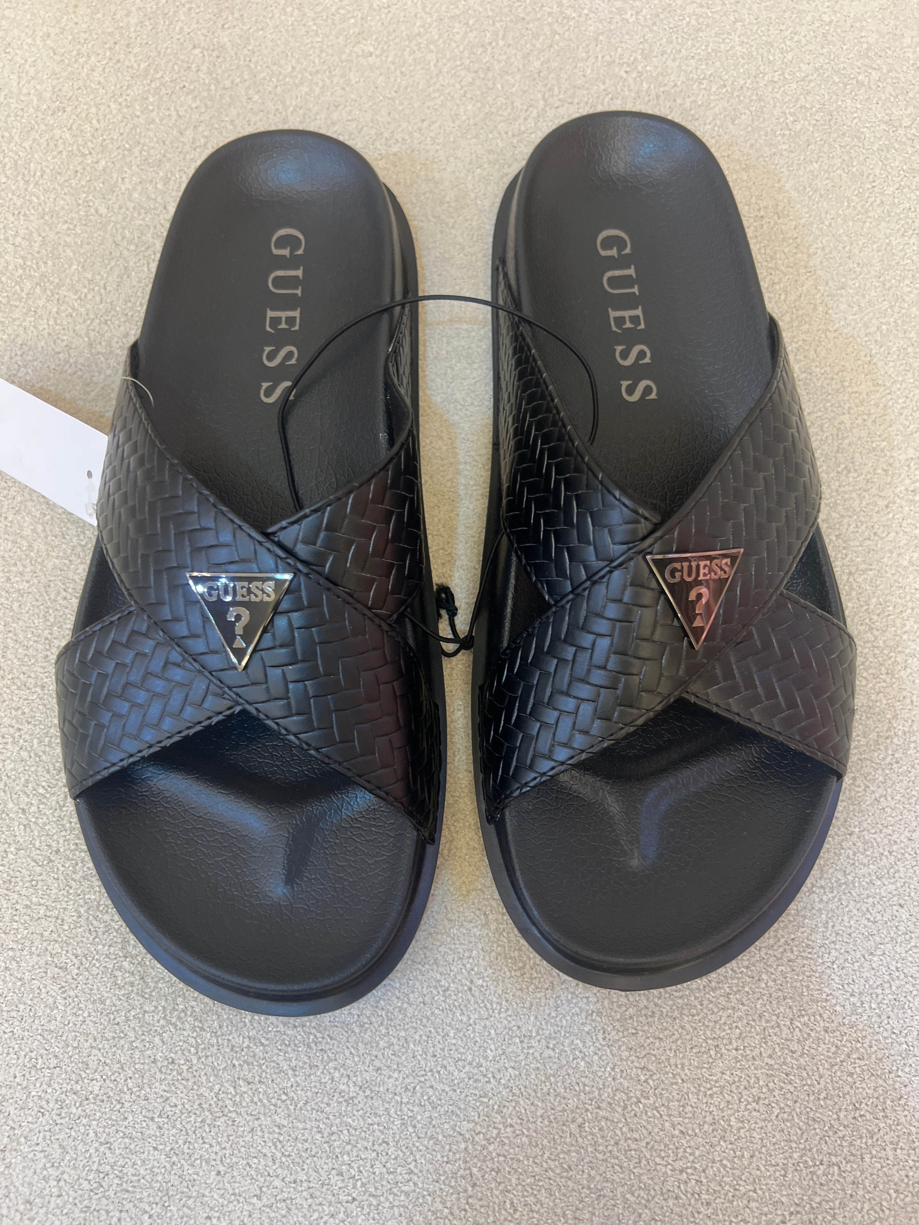 GUESS black Banlin slide sandals featuring a woven design and a silver triangular logo
