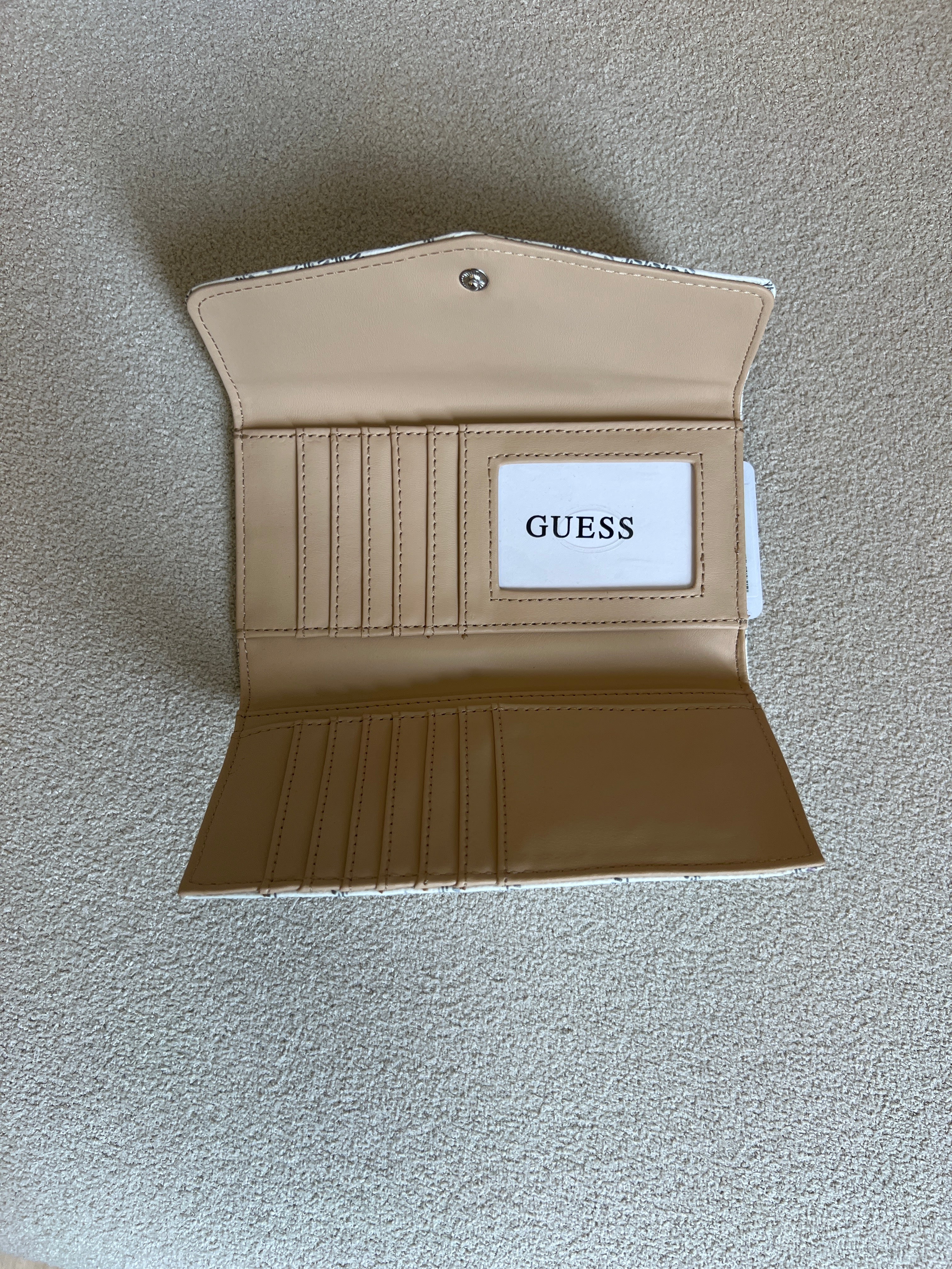 Guess Granby SLG Slim Clutch features an all-over logo print and a snap button closure