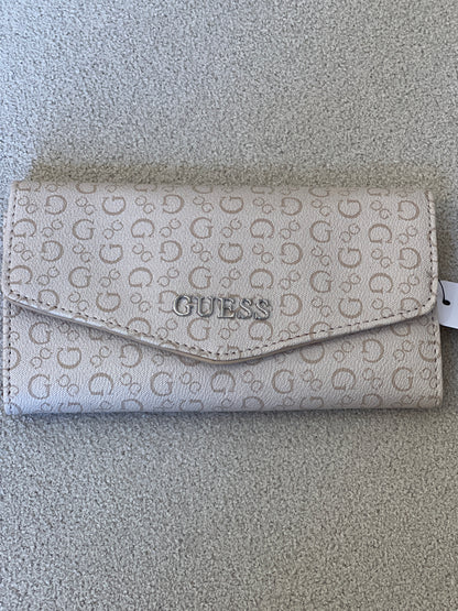 Beige Guess monogram clutch wallet features a silver-tone logo emblem on the front flap