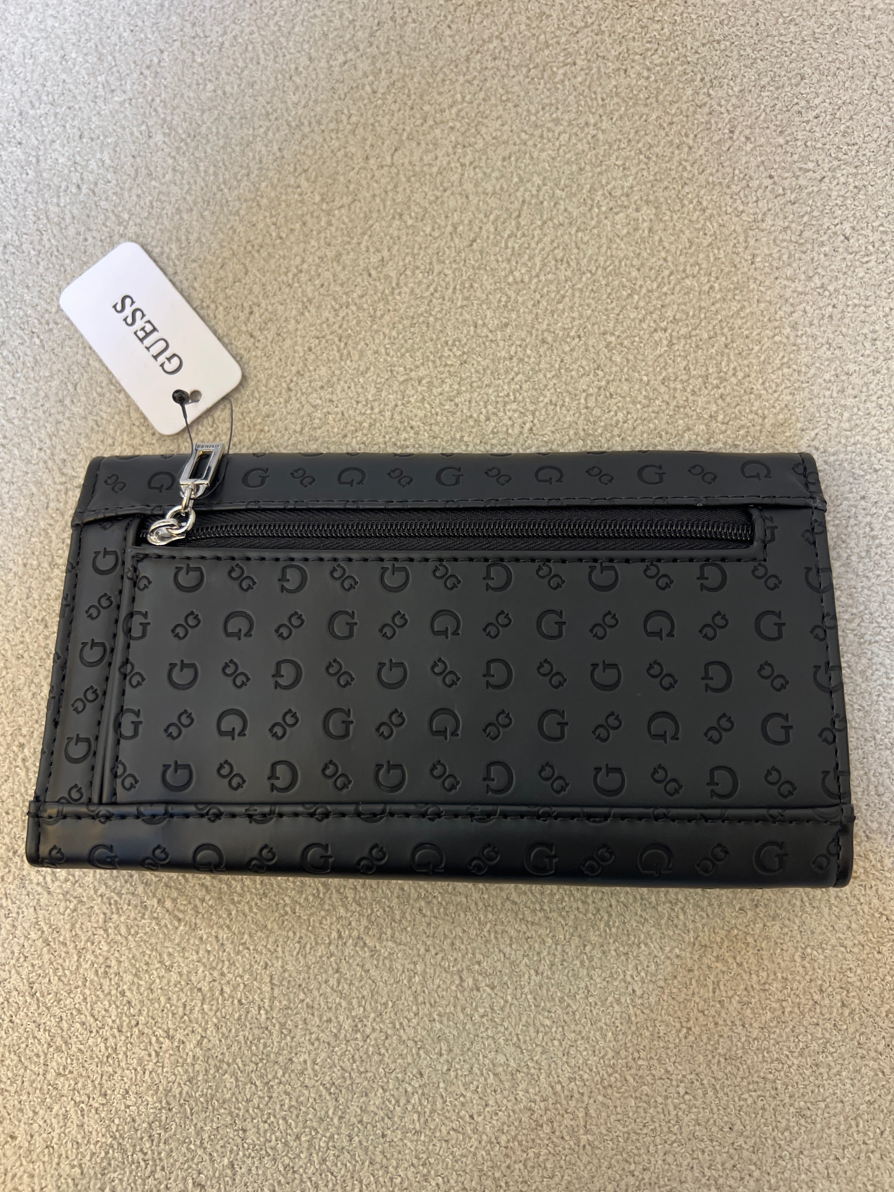 Guess monogram wallet features a distinctive embossed logo pattern and a snap closure