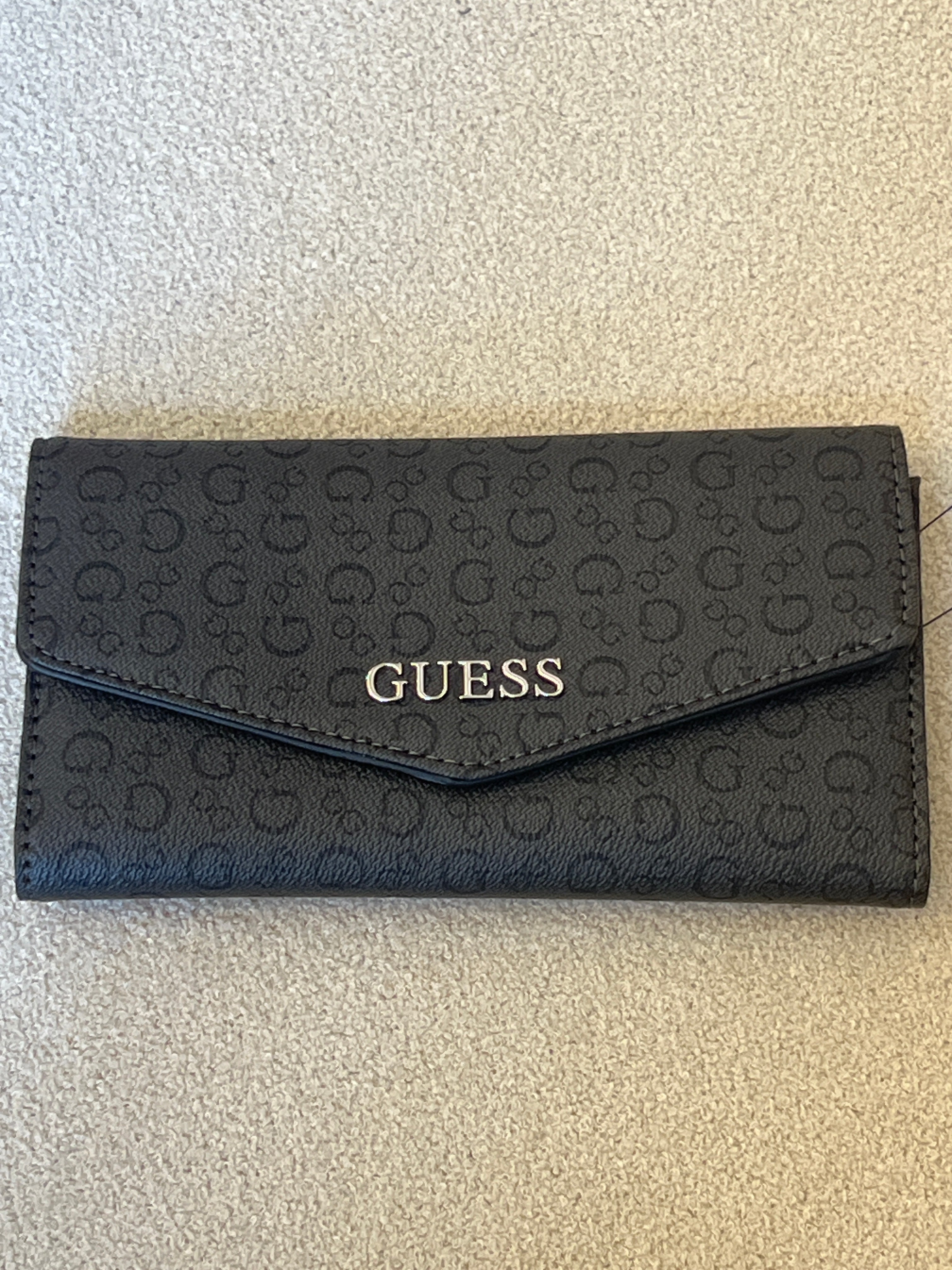 Guess clutch wallet featuring an all-over monogram logo print and a snap-flap closure