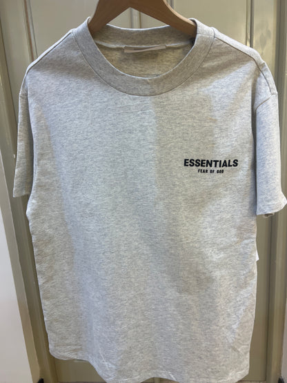 Fear of God Essentials T-shirt features a light oatmeal heather fabric and a contrasting black logo on the chest