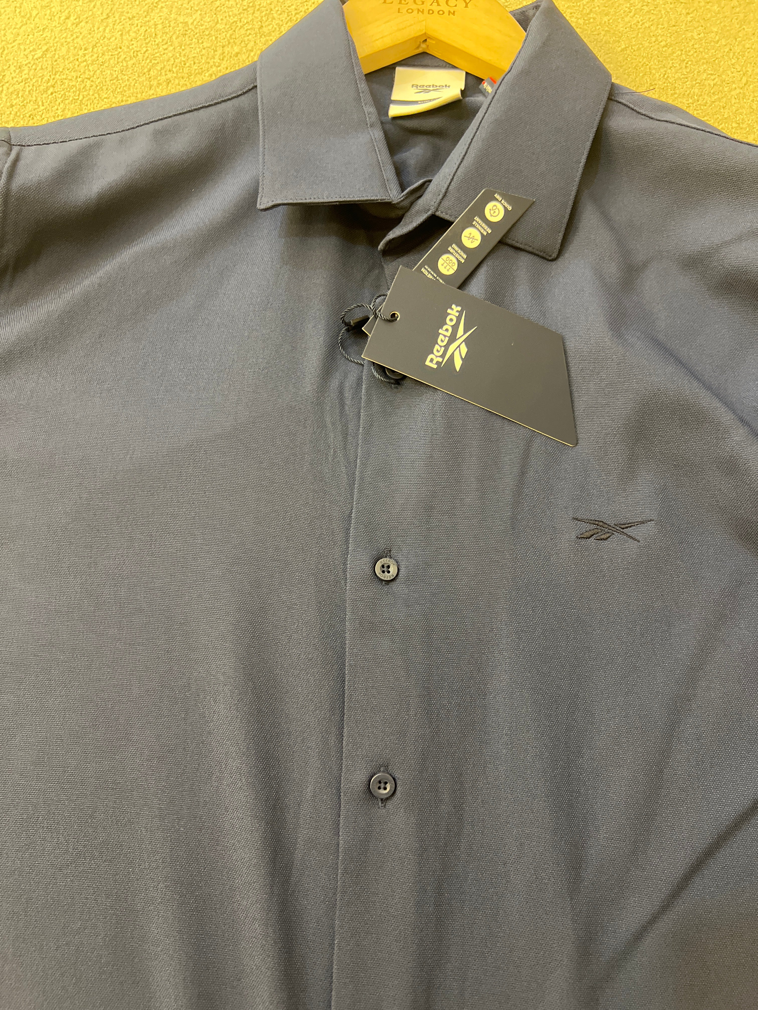 Reebok brand shirt is a navy blue long-sleeved garment featuring a slim fit and a classic collar
