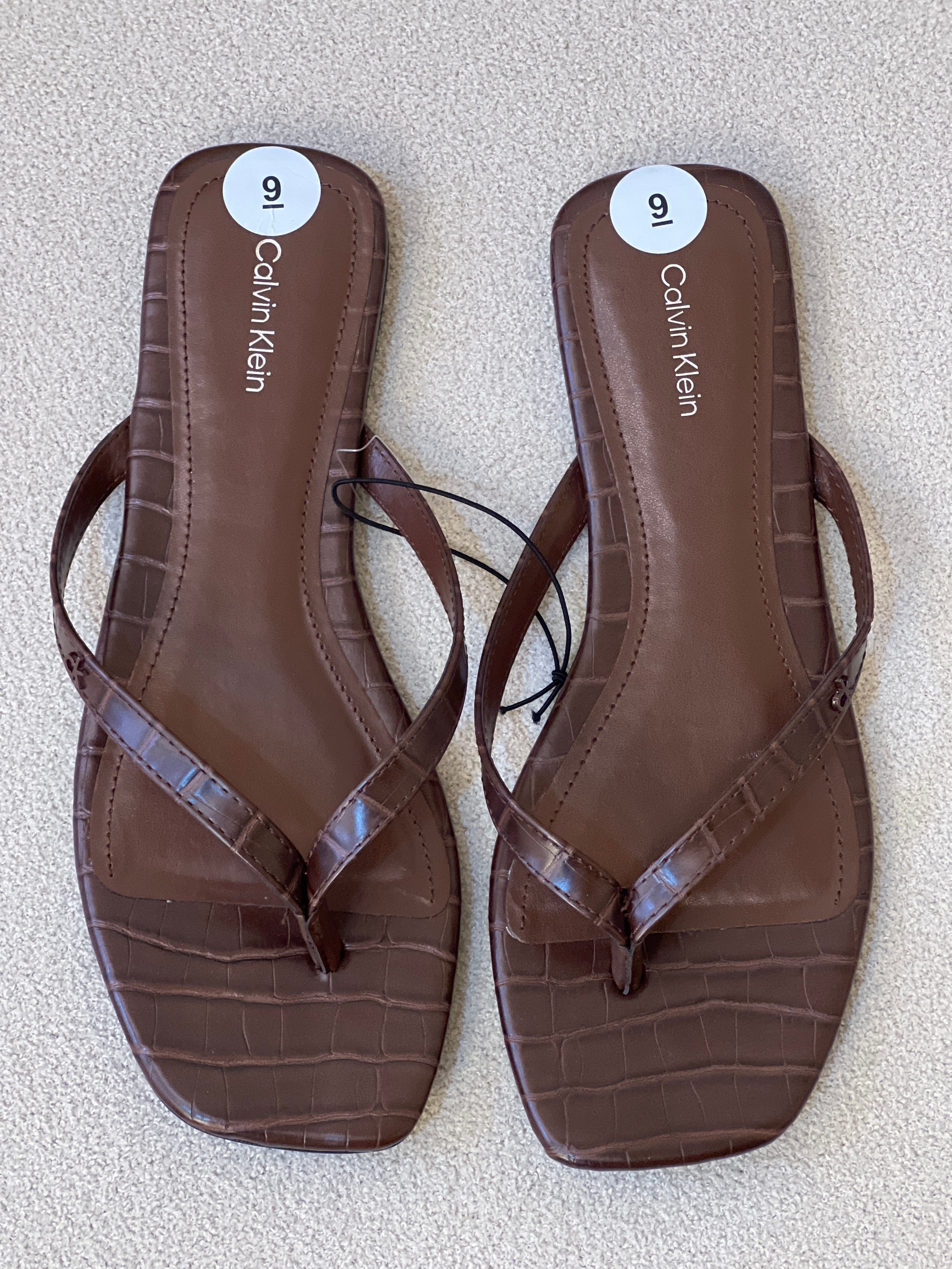 Calvin Klein brown faux-croc thong sandals are a stylish and comfortable footwear option featuring a flat sole and embossed detailing