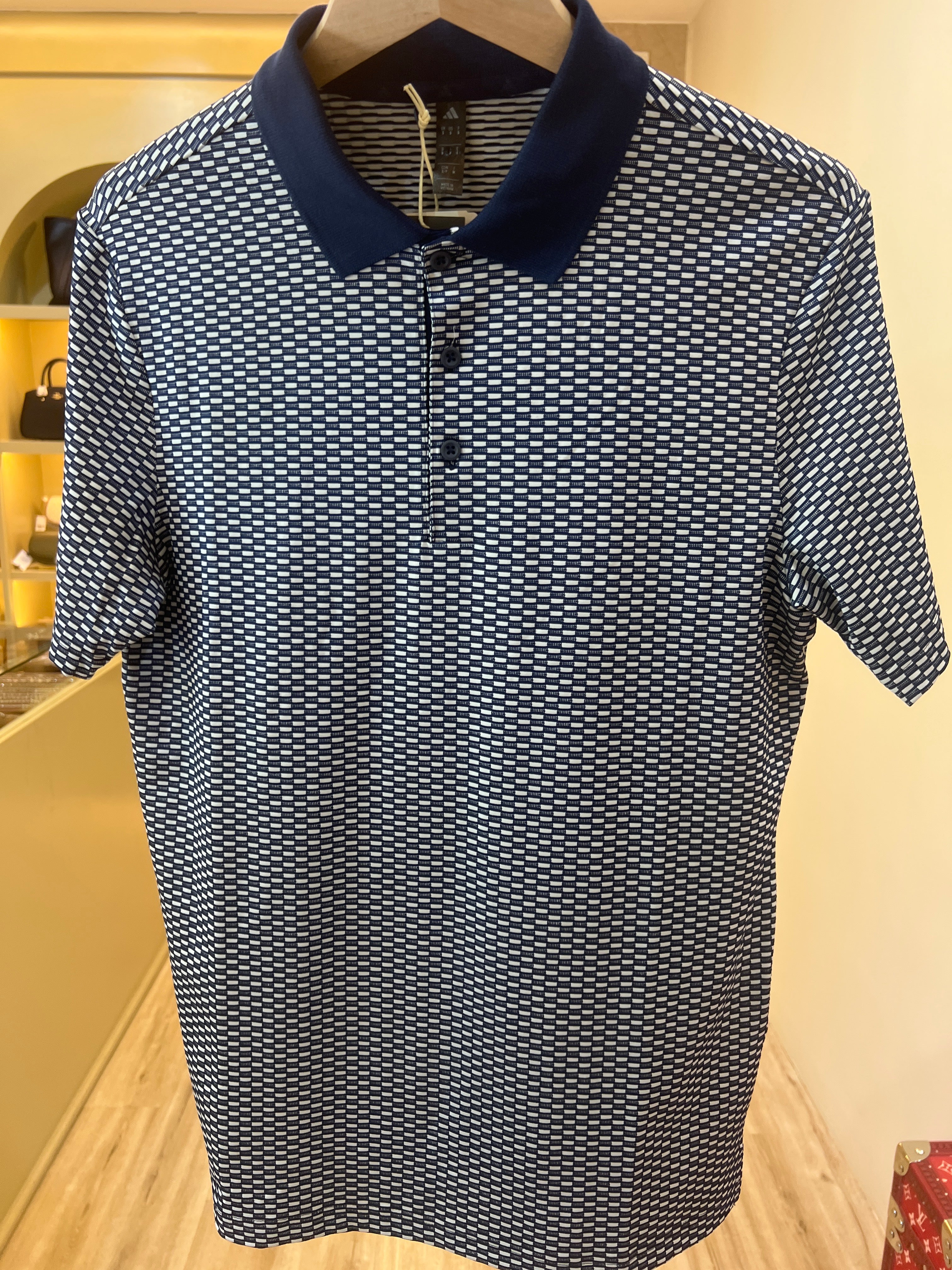 Adidas polo shirt featuring a textured geometric pattern and a contrasting dark navy collar