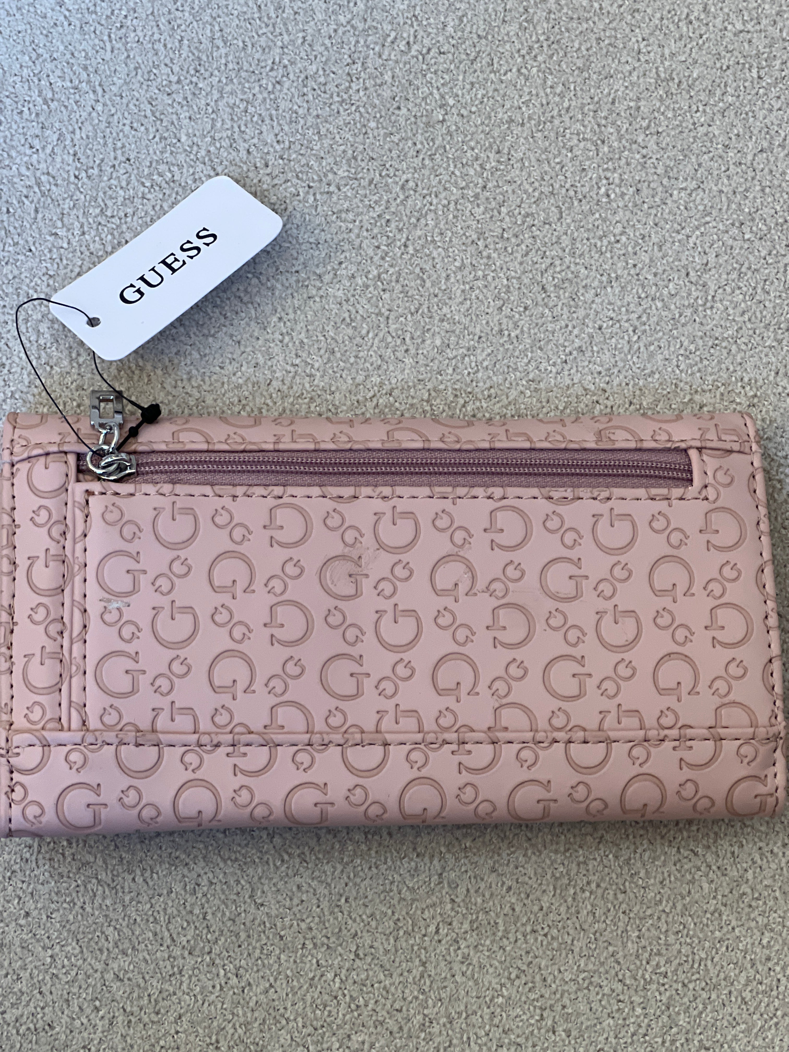 Guess Viviette tri-fold wallet features a textured, light pink monogram exterior and a prominent triangular logo plaque