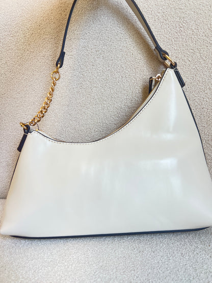 Guess Noelle top zip shoulder bag features a sleek white faux leather exterior with a distinctive triangular logo plaque