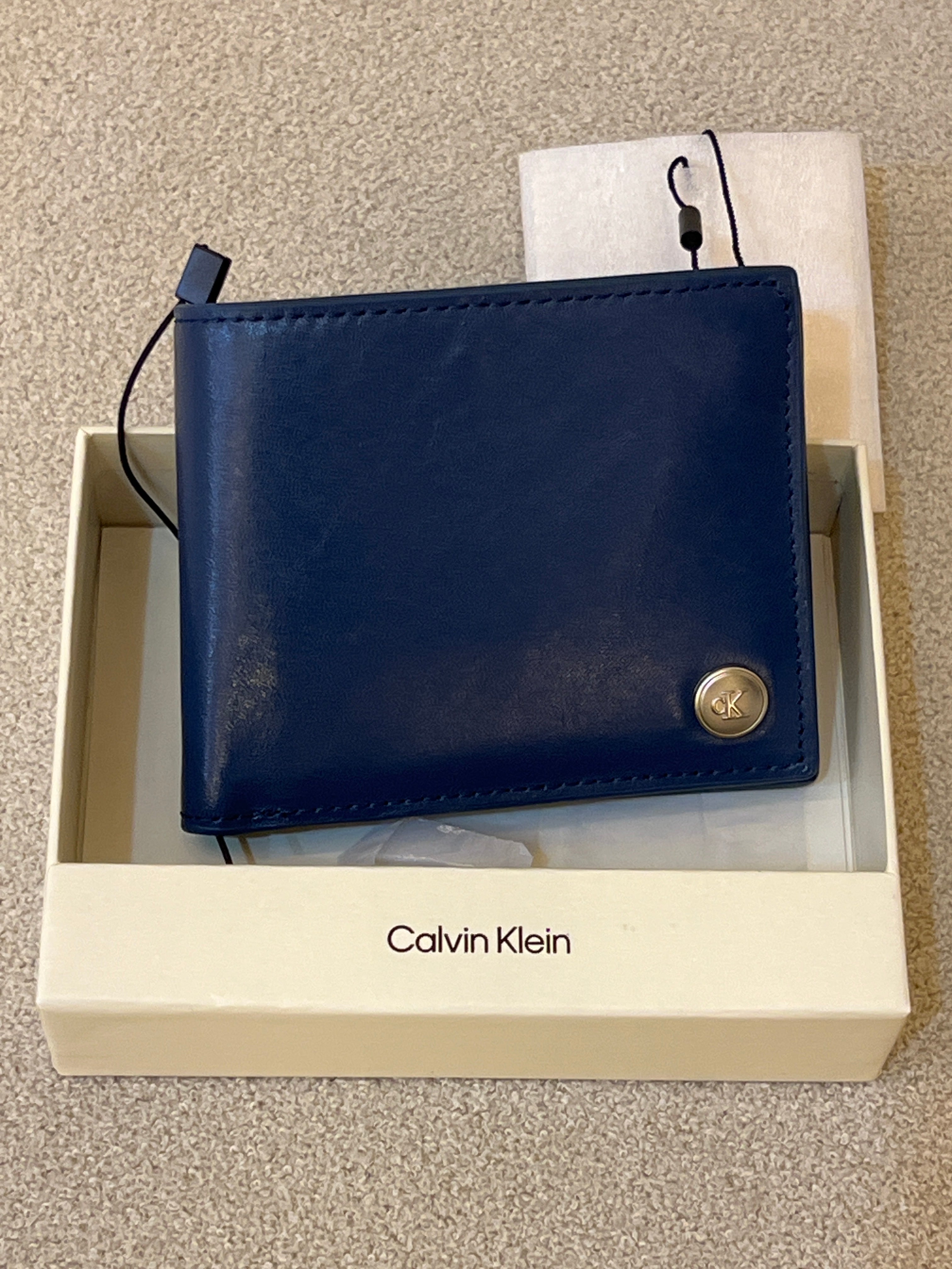 Calvin Klein wallet features a minimalist design with a small silver logo stud on the corner