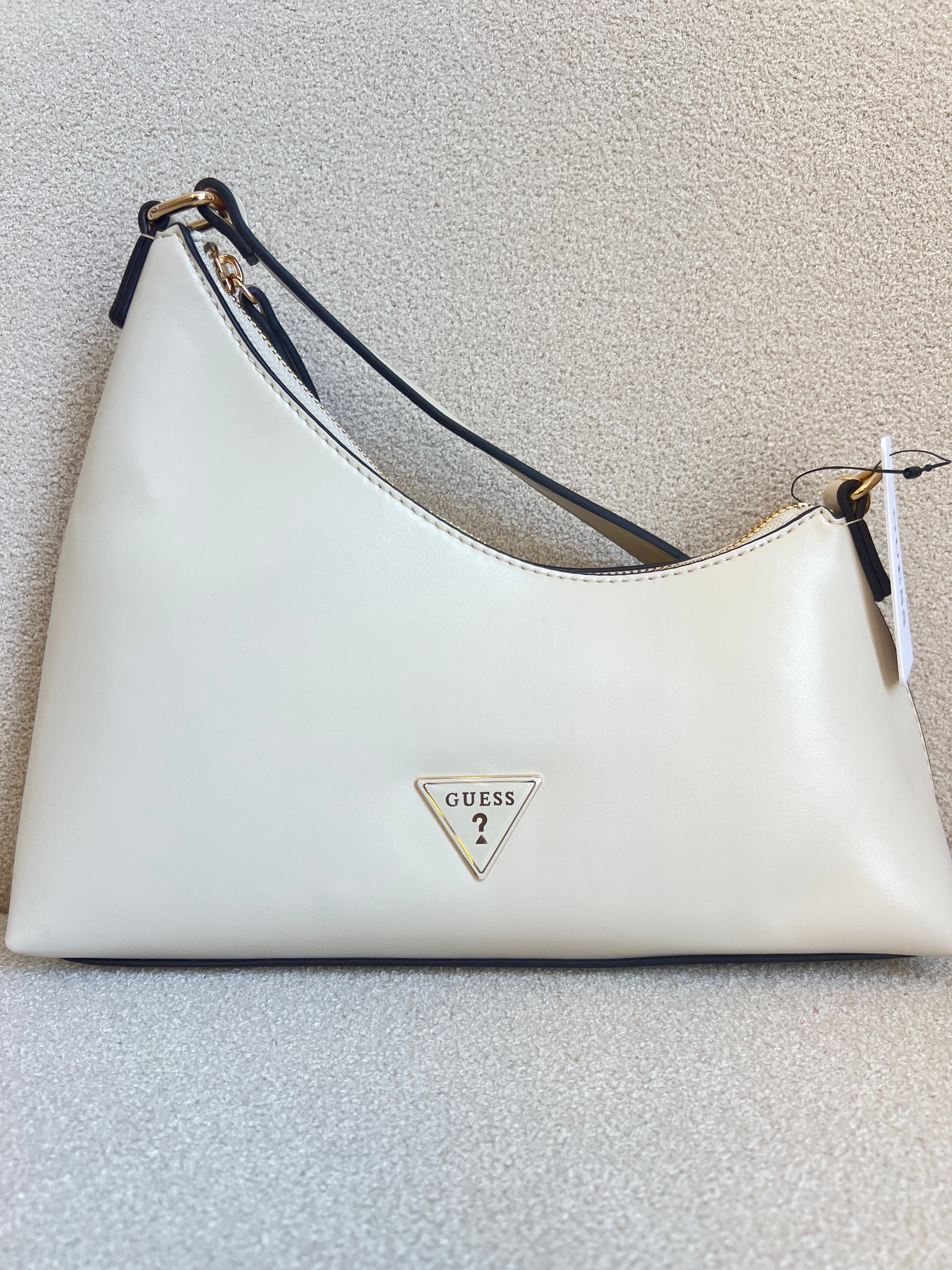 Guess Noelle top zip shoulder bag features a sleek white faux leather exterior with a distinctive triangular logo plaque