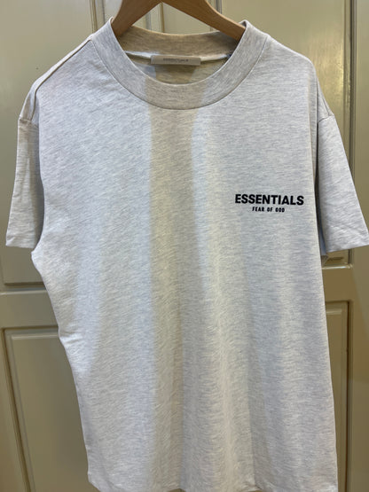 Fear of God Essentials T-shirt in light oatmeal features a distinct black logo graphic on the chest
