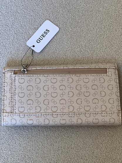 Beige Guess monogram clutch wallet features a silver-tone logo emblem on the front flap