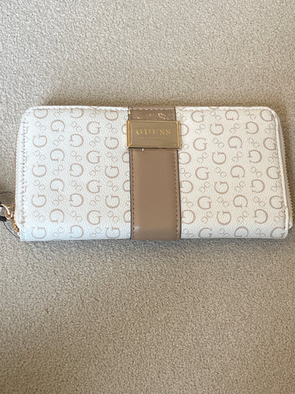 Guess Isabella zip-around wallet features a white printed design with a tan center strap and a prominent gold logo plaque