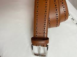 Cole Haan men's perforated leather belt is a tan-colored accessory featuring a polished silver buckle